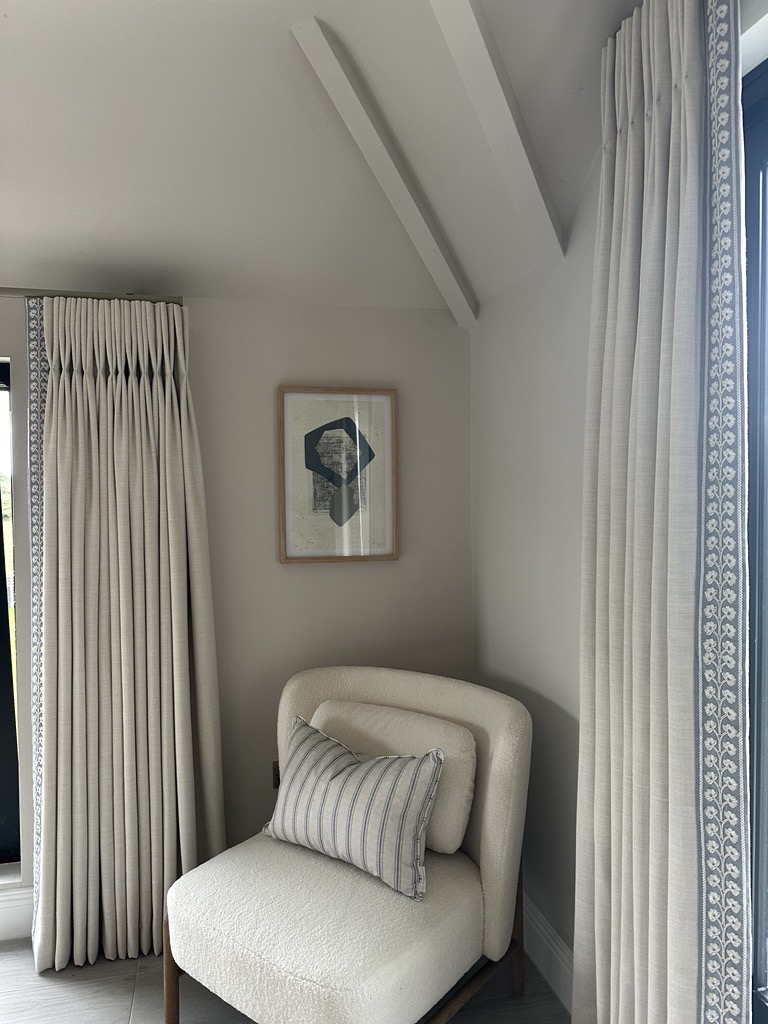 Detail of a white bouclé chair and soft curtains